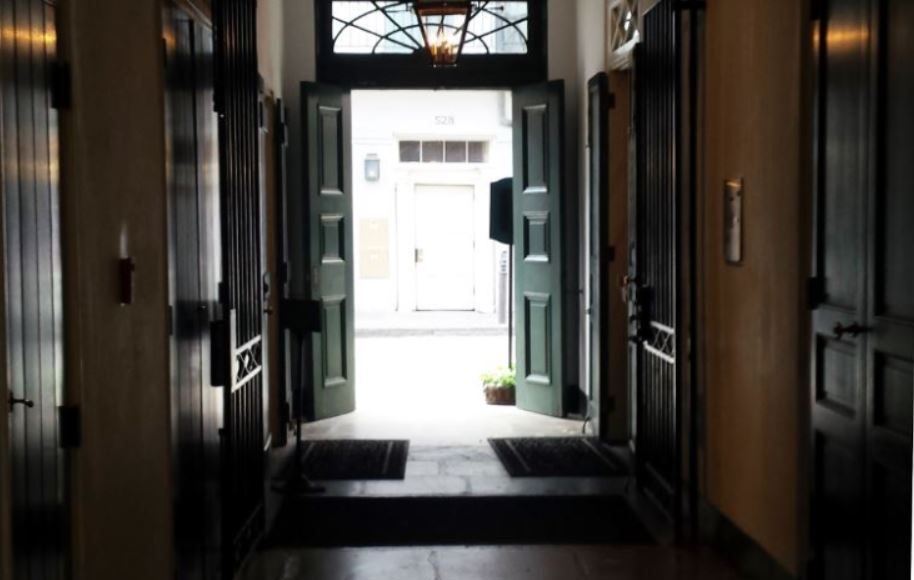 Looking out of dark hallway with doors in each side to two open doors with bright light illuminating the darkness.